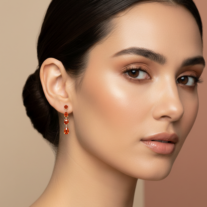 Woman wearing orange sapphire drop earrings against a beige background