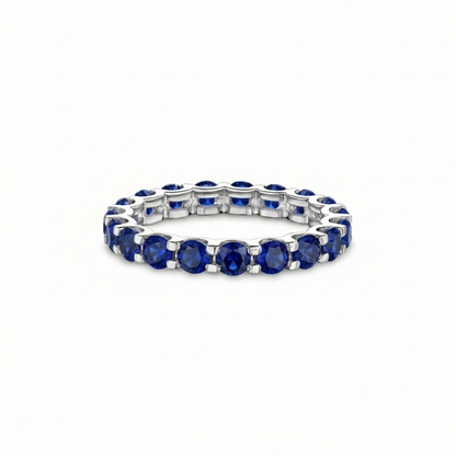 white gold full eternity ring with blue sapphires; the ring is presented on a white background