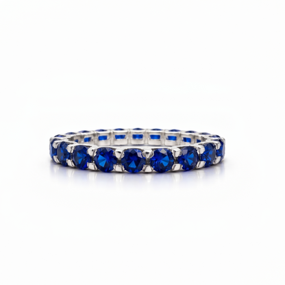 White gold eternity ring with blue sapphires on a white background