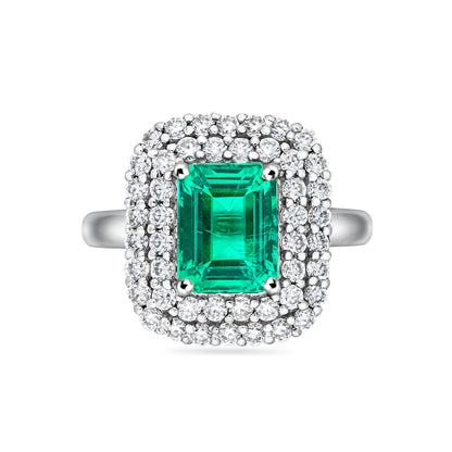 White gold ring with an emerald cut Colombian emerald and diamond double halo vintage inspired style, on a white background