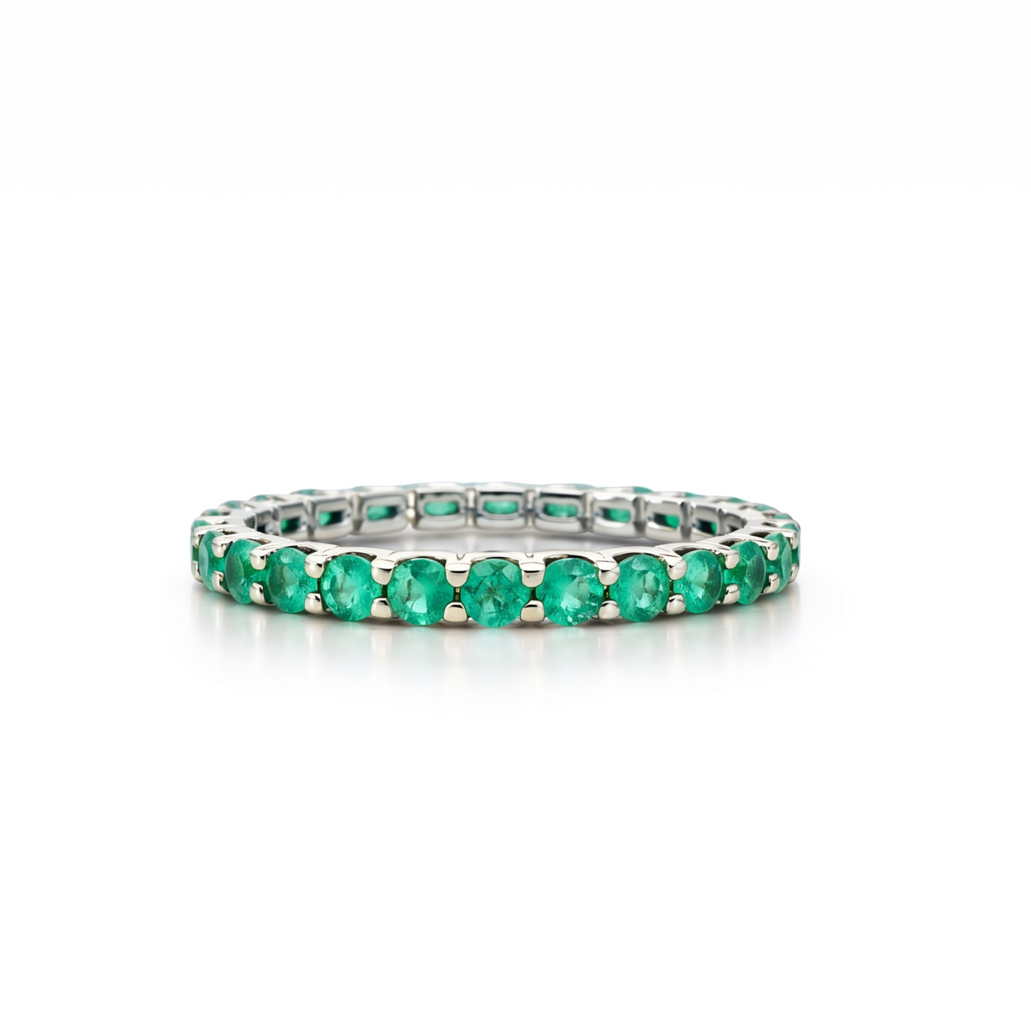 Eternity white gold ring with emerald stones on a white background