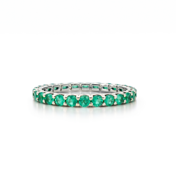 Eternity white gold ring with emerald stones on a white background