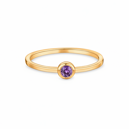 Gold ring with a purple ametyst, bezel set, on a white background